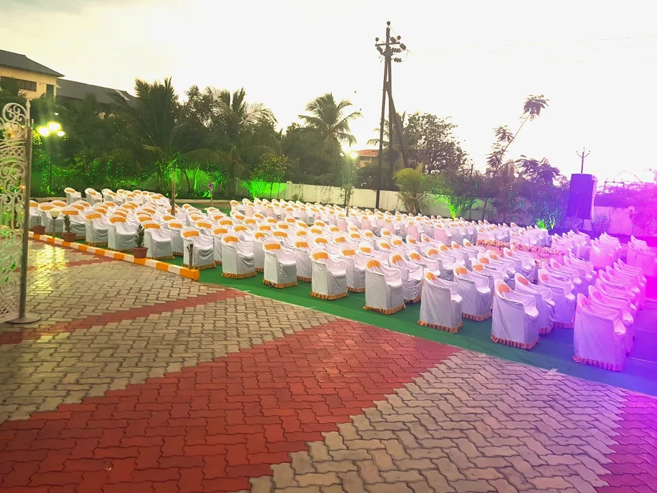 Garden lawn set for an event, with white chairs and evening lights